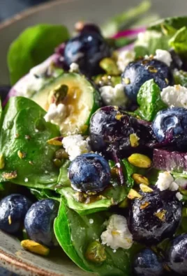 Blueberry pistachio spring salad with fresh greens and colorful toppings.