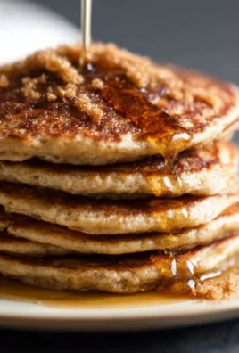 Delicious cinnamon brown sugar pancakes stacked with syrup and cinnamon sprinkle.