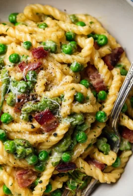 Creamy pea and pancetta pasta dish garnished with herbs