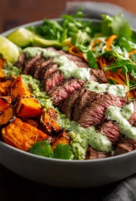 Steak and sweet potato bowls with avocado-cilantro drizzle on a wooden table.