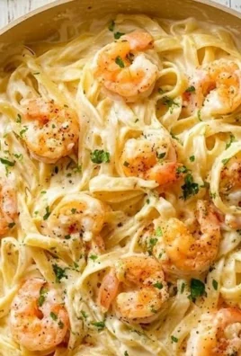 Plate of Classic Shrimp Fettuccine Alfredo garnished with fresh herbs