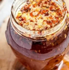Homemade hot honey in a jar with chili peppers and drizzle on food