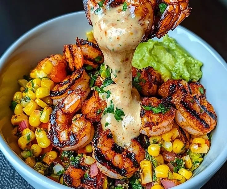 Grilled shrimp bowl with avocado, corn salsa, and creamy sauce on a plate