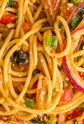 A vibrant bowl of spaghetti salad with vegetables and dressing