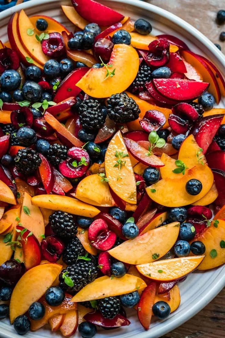 Colorful summer fruit salad with lemon maple thyme dressing in a bowl