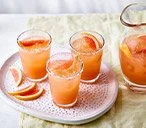 Big-batch paloma cocktail garnished with lime and served in a glass