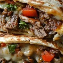 Crispy Philly cheesesteak grilled wraps on a plate with fresh ingredients.
