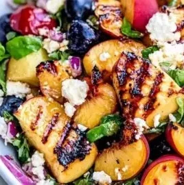 Delicious grilled peach salad served with greens and dressing.