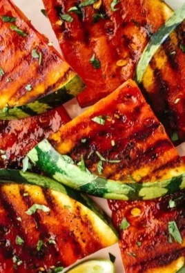 Grilled watermelon slices drizzled with honey and lime juice on a plate.