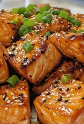 Honey garlic salmon bites served on a plate, garnished with green onions.