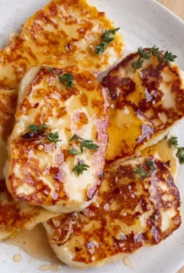Grilled Hot Honey Halloumi cheese drizzled with spicy honey and garnished with herbs.