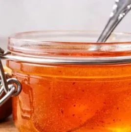 A jar of homemade hot honey recipe with chili pepper flakes.