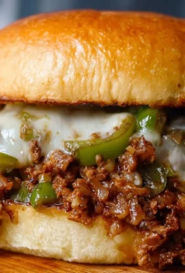 Plate of Philly Cheesesteak Sloppy Joes topped with melted cheese and peppers