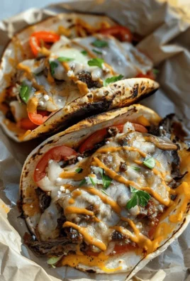 Philly cheesesteak smash burger tacos served on a plate