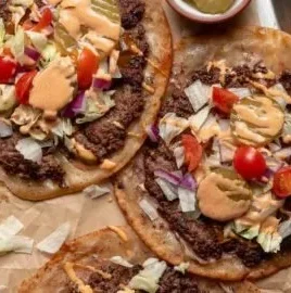 Smash burger tacos with special sauce on a wooden serving board
