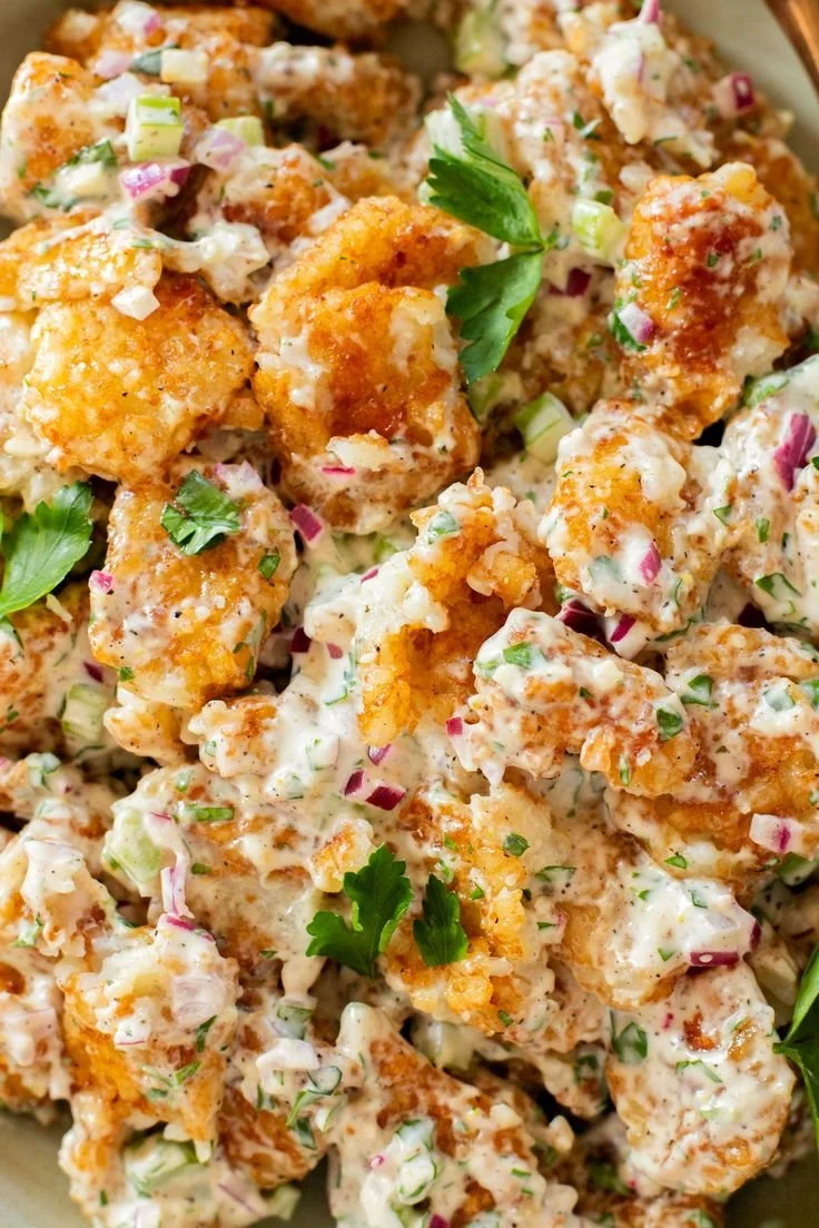 Smashed tater tot potato salad served in a bowl with fresh herbs