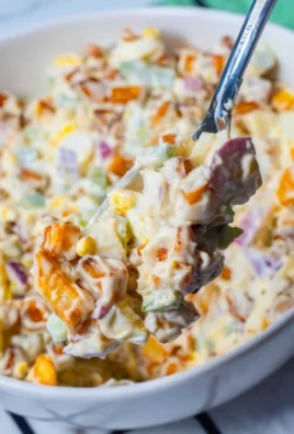 A bowl of unique potato salad with colorful ingredients and fresh herbs