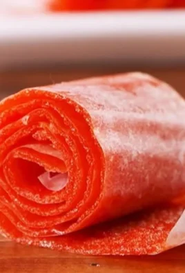 Homemade watermelon fruit roll-ups on a wooden table