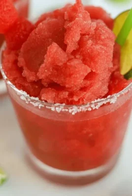 Refreshing watermelon slushie in a clear glass with ice and mint garnish