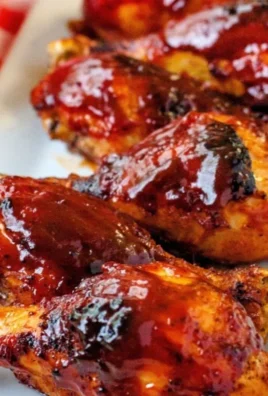 Baked BBQ chicken drumsticks served on a plate with a side of dipping sauce.