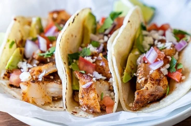 Baked fish tacos topped with fresh ingredients in warm tortillas