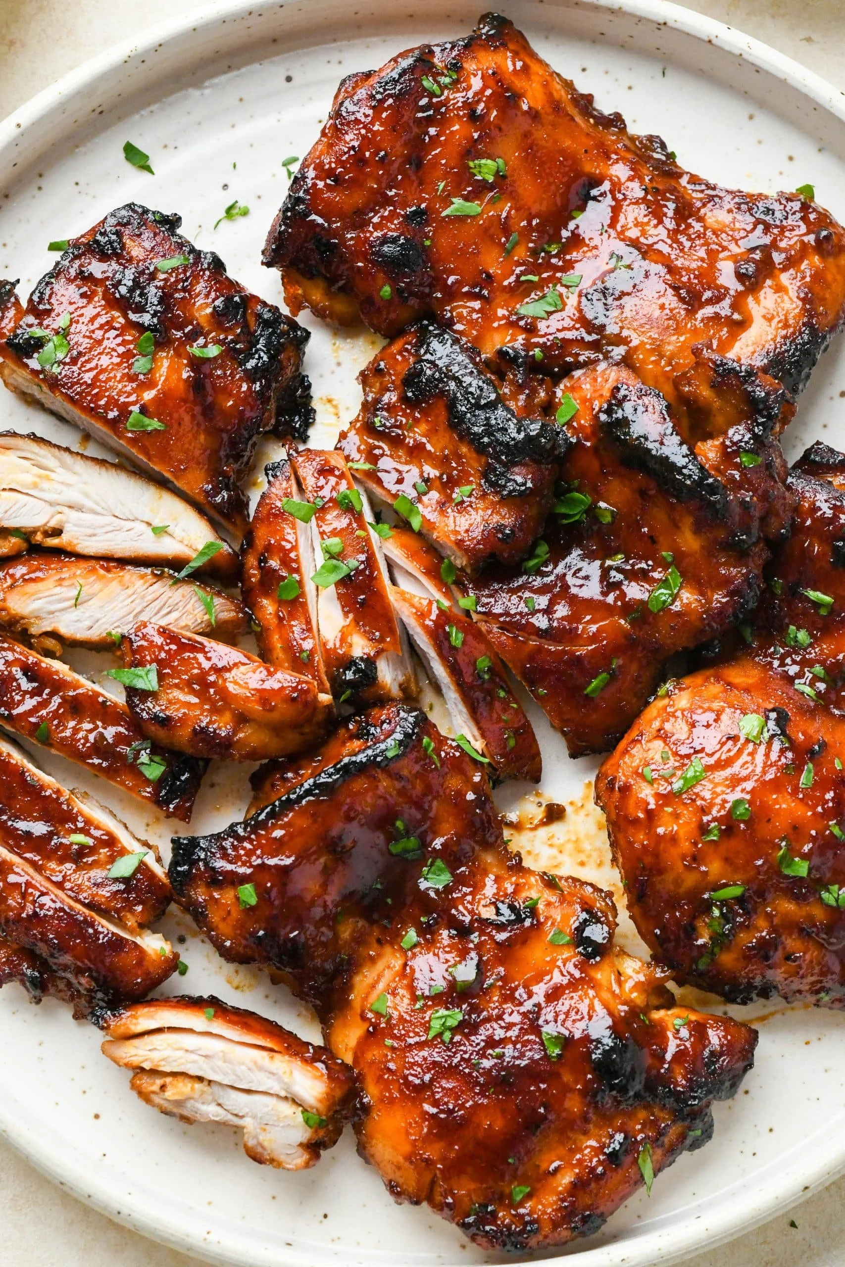 Caramelized BBQ chicken thighs fresh out of the oven, glistening with sauce.