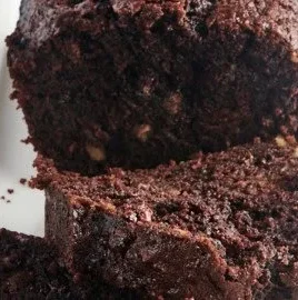 Slice of moist chocolate zucchini bread with chocolate chips on a wooden board