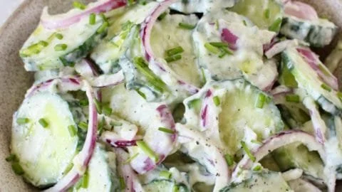 Creamy cucumber yogurt salad served in a bowl with herbs.