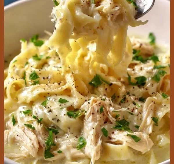 Bowl of easy creamy chicken noodles topped with parsley and pepper