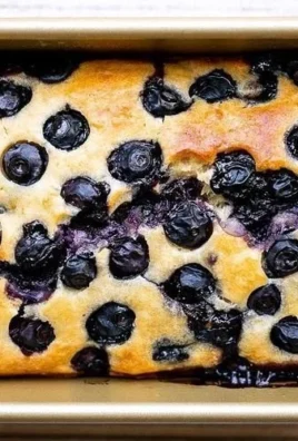 Sliced easy lemon blueberry bread garnished with fresh blueberries and lemon zest.
