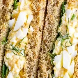 Bowl of egg salad with dill garnished with fresh herbs