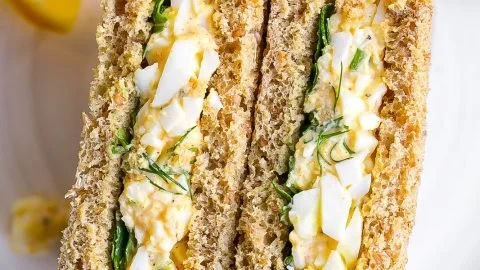 Bowl of egg salad with dill garnished with fresh herbs