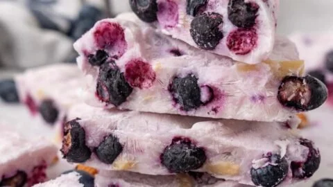 Frozen yogurt bark topped with blueberries and almonds on a wooden surface.