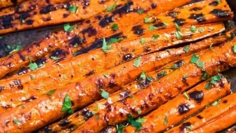 Grilled carrots glazed with a sweet sauce on a serving plate.