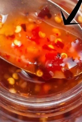 Bottle of homemade sweet chili sauce with fresh ingredients.