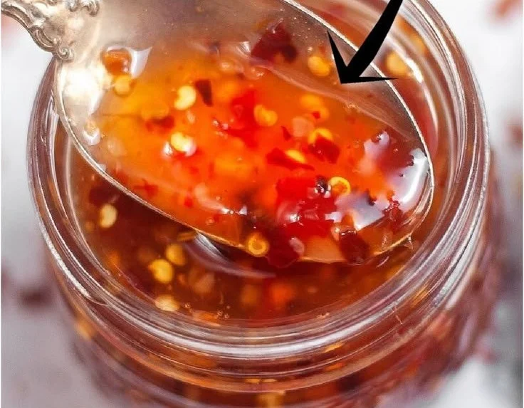 Bottle of homemade sweet chili sauce with fresh ingredients.