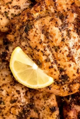 Marinated lemon pepper chicken ready for grilling with fresh herbs and spices.
