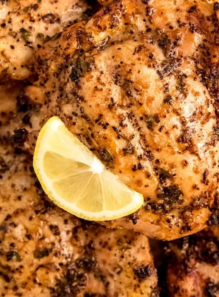 Marinated lemon pepper chicken ready for grilling with fresh herbs and spices.
