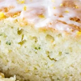 Sliced lemon zucchini bread on a wooden board, showcasing its moist texture and lemon zest.