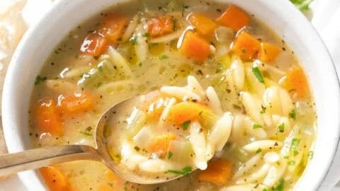 Bowl of hearty Orzo Soup with vegetables and herbs
