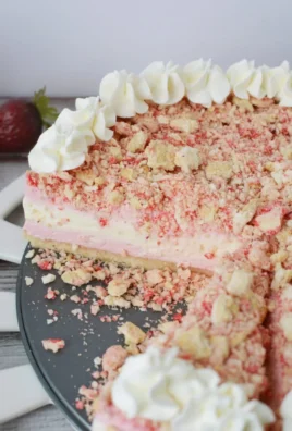 Slice of Strawberry Crunch Cheesecake topped with fresh strawberries and crunchy crumbs.