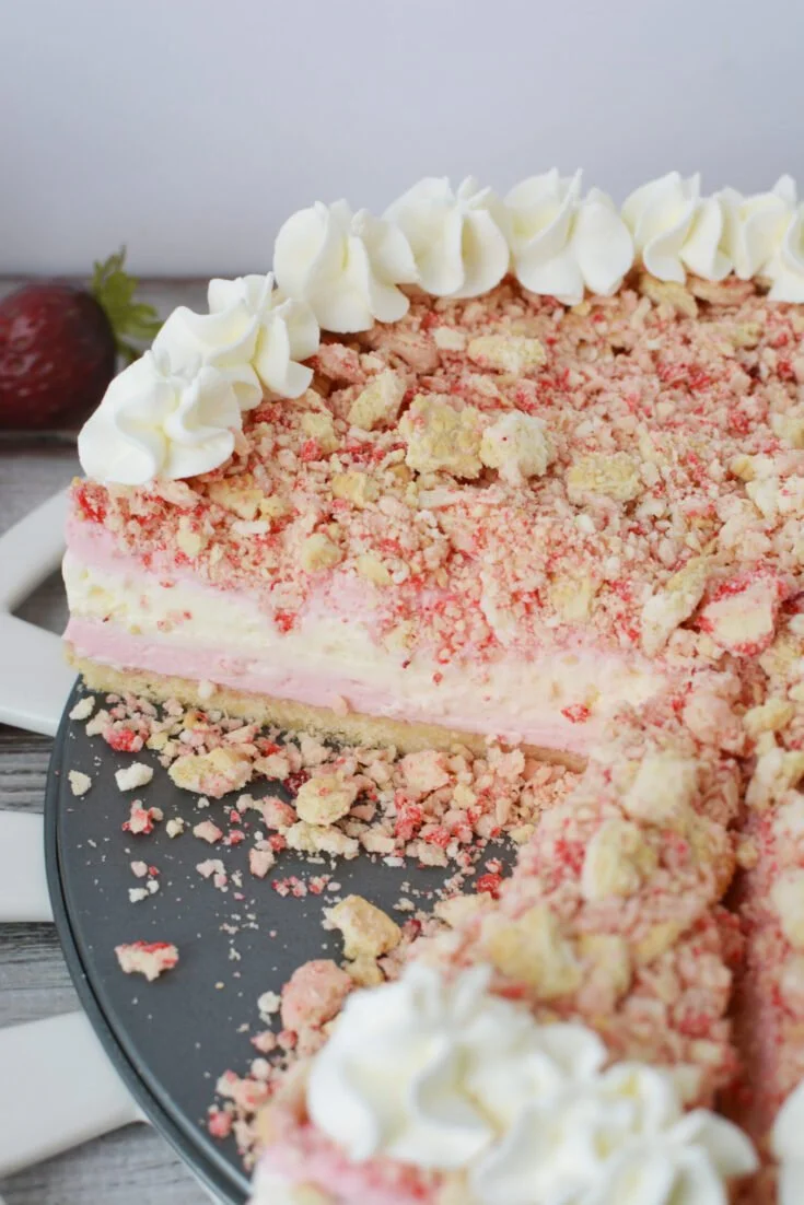 Slice of Strawberry Crunch Cheesecake topped with fresh strawberries and crunchy crumbs.