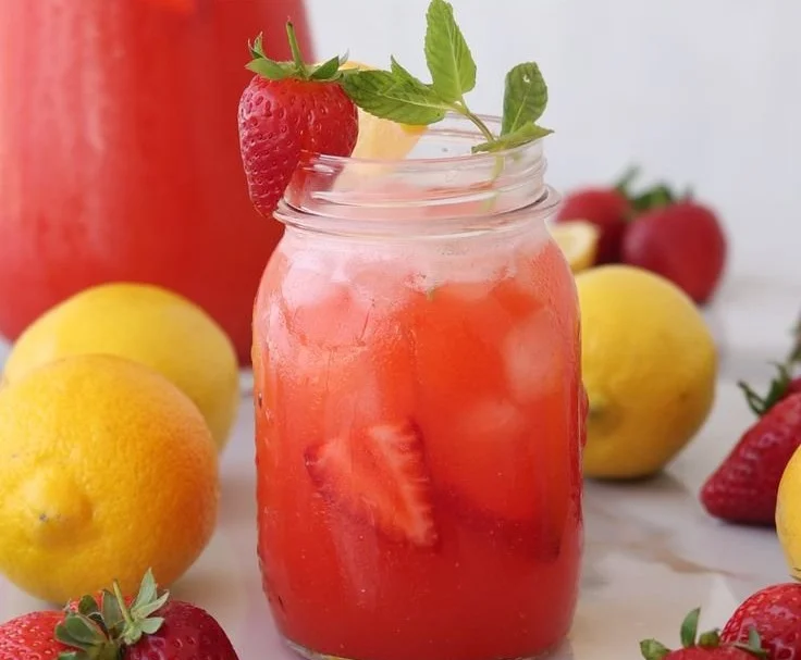 Refreshing glass of strawberry lemonade with fresh strawberries and lemon slices