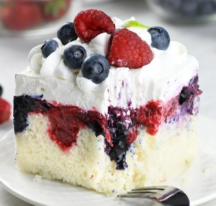 Delicious Summer Berry Poke Cake topped with fresh berries and cream